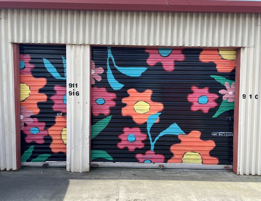Storage roll-up doors painted with a bright flower mural at Bridge