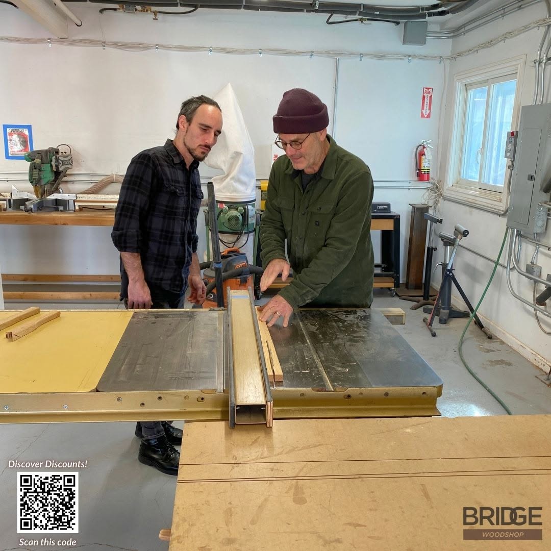 Two makers working together at a table saw in the Bridge woodshop